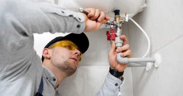 Professional plumber adjusting components on an overhead water heater