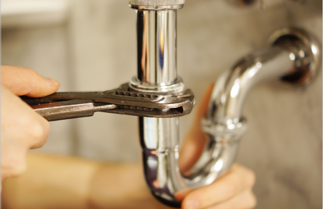 A commercial plumber inspecting pipes in a Naperville business