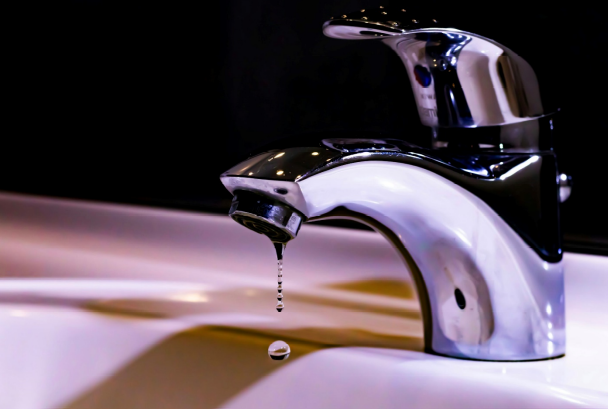 A close-up of a dripping bathroom faucet indicating a slow leak.