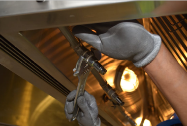 A plumber fixing a pipe with a spanner