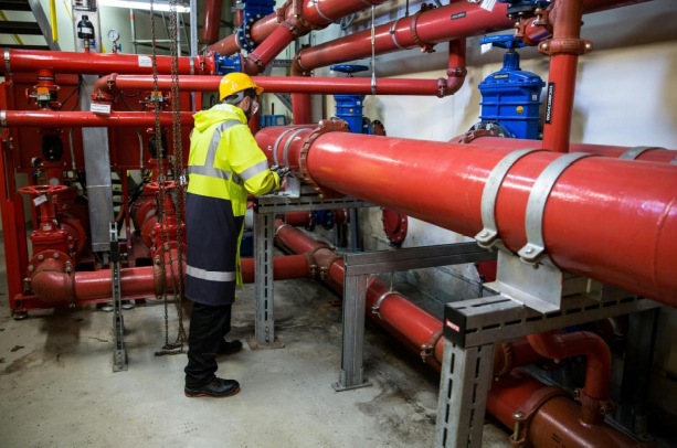 a plumber in safety gear inspecting gas pipes